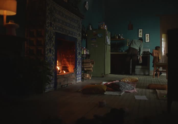 A girl walks up to her father in their kitchen