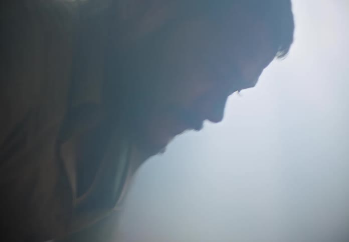 Unconscious man laying on the floor of a room full of smoke shakily stands up