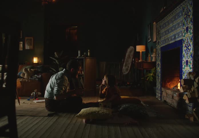 Father and daughter are sitting on the ground by the fire place