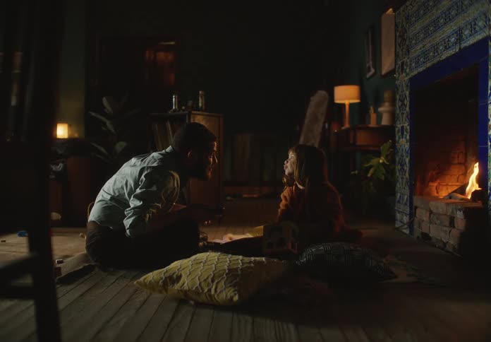 A father and daughter on the floor talking as the daughter plays with a box