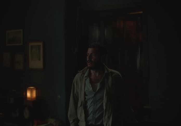 Man walking inside a dimly lit house climbs up the stairs to the second floor