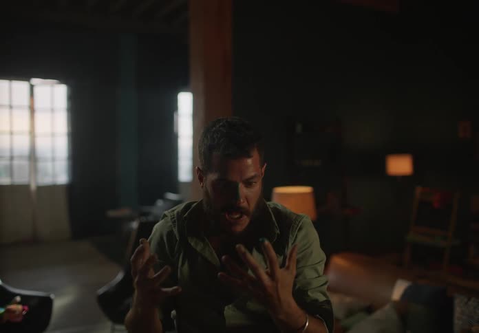Man standing in home stares at stained hands before turning and flinging his hands forward