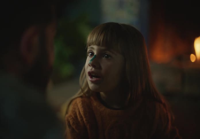 A daughter is talking to her father by the fireplace