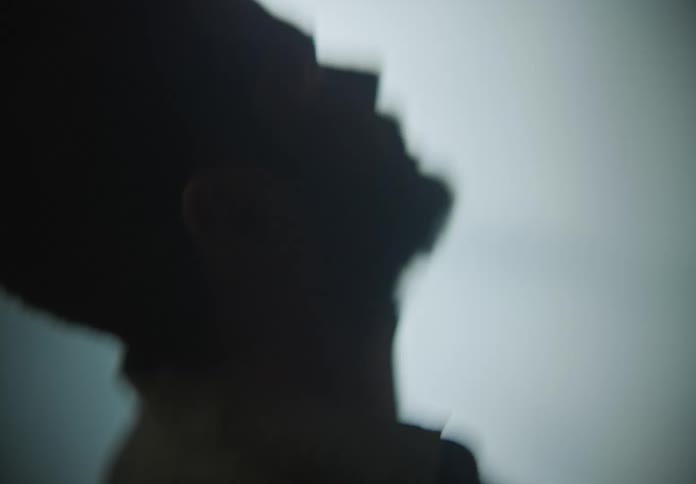 Blurry close up of the head of a weak man kneeling on the floor of a room filled with smoke