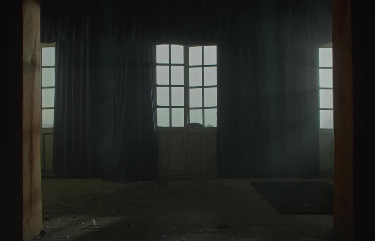 Dust and litter covers floor of empty room with multiple windows