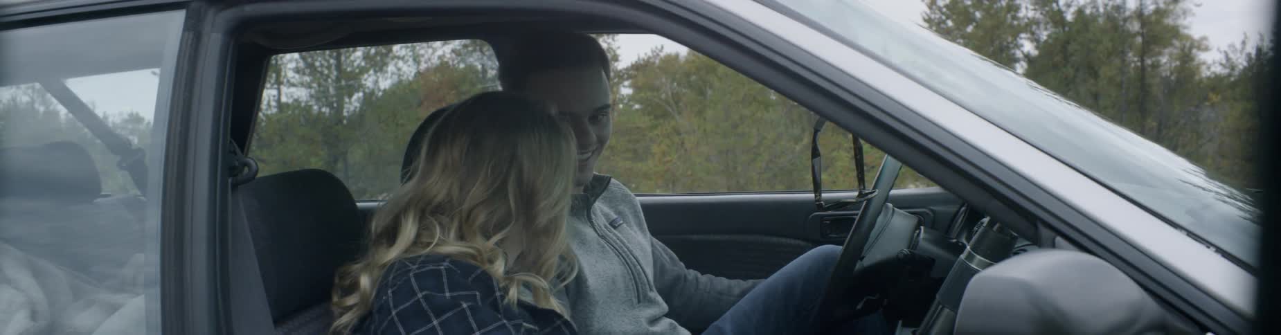 A boy and a girl laughing in a car