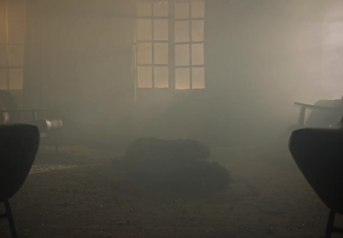 An unconscious person curled on the floor of a room filled with smoke