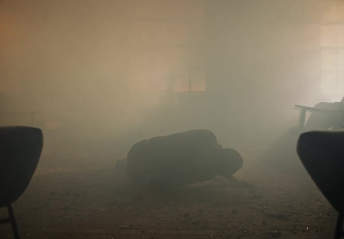 Man struggles to rise in smoky house after red glow of outdoor fire and destruction fades somewhat
