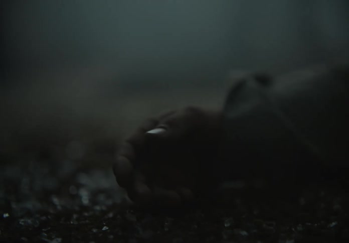 Right hand with a loosely cuffed sleeve above lays on gravel