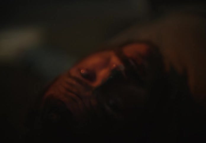 Unconscious man laying with his eyes open on the floor of a dimly lit room