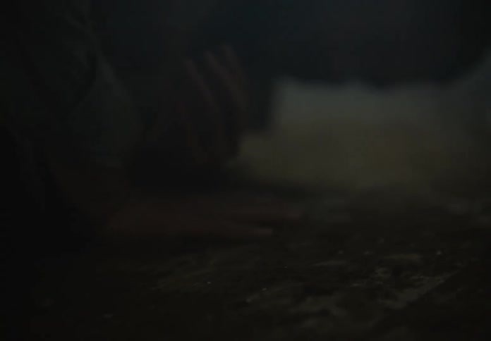 Unconscious man laying on the floor of a room filled with smoke stands up shakily