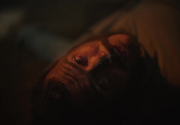 Man lies on his back in dim room staring