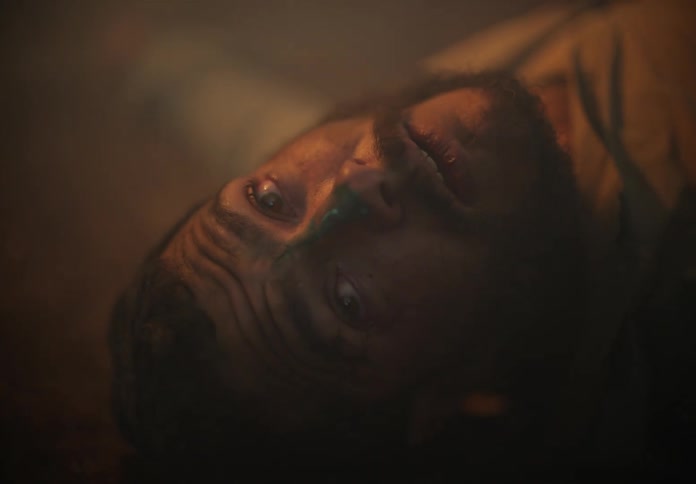 A man with black face paint is laying on the ground