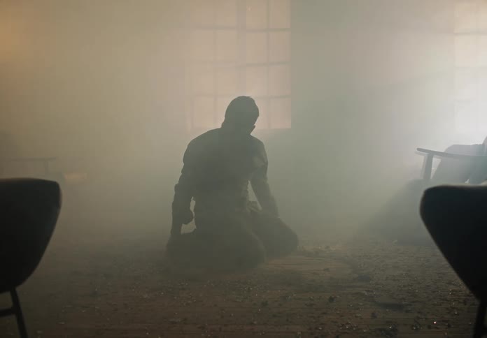 Distressed man crawling in a smoked filled room