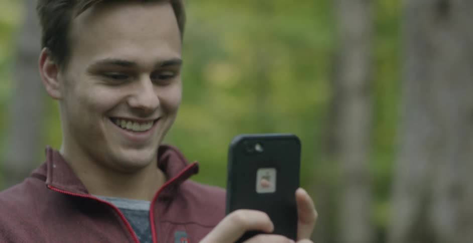 A man takes a photo with his phone in the woods