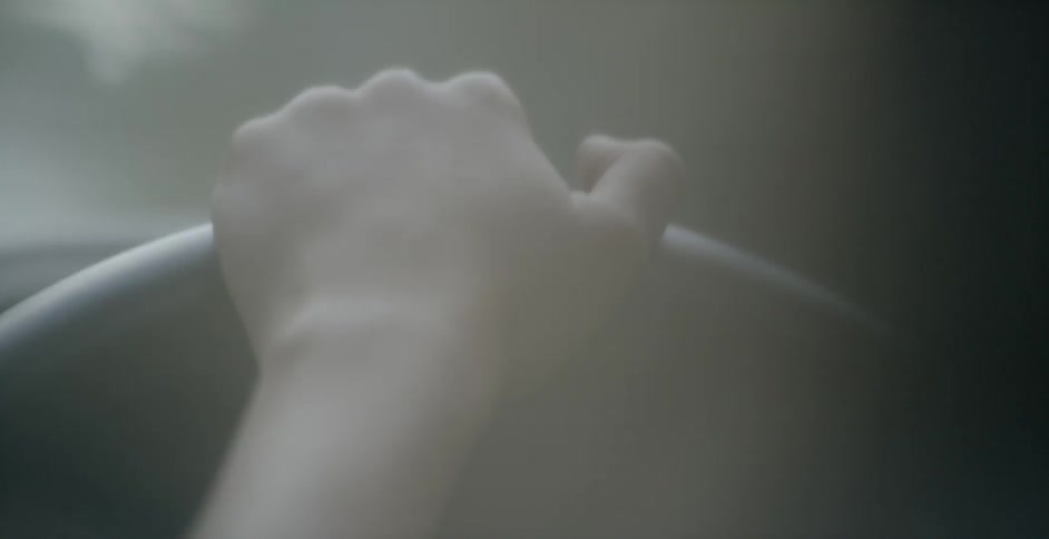 A hand rests on a steering wheel