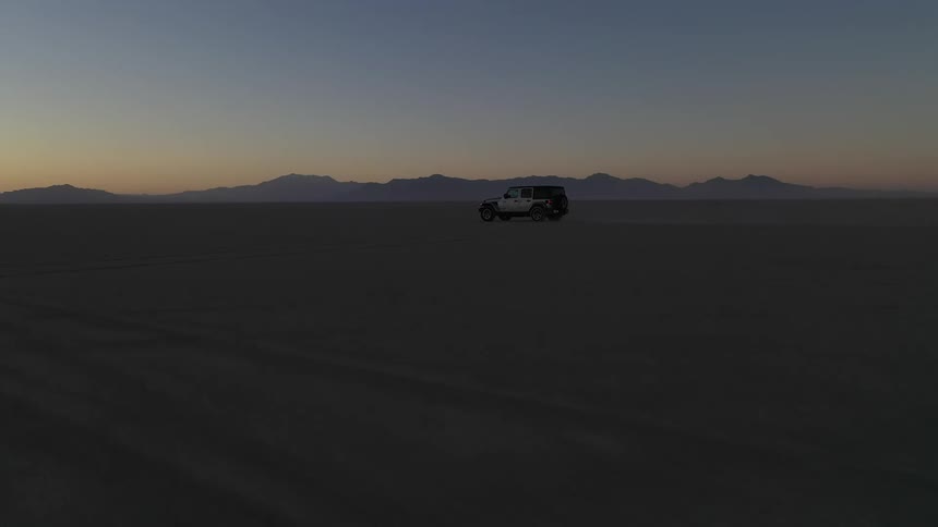 A jeep speeds through a vast dessert