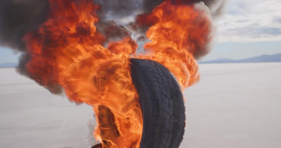 Tire standing inside a bucket engulfed in flames in the middle of the desert