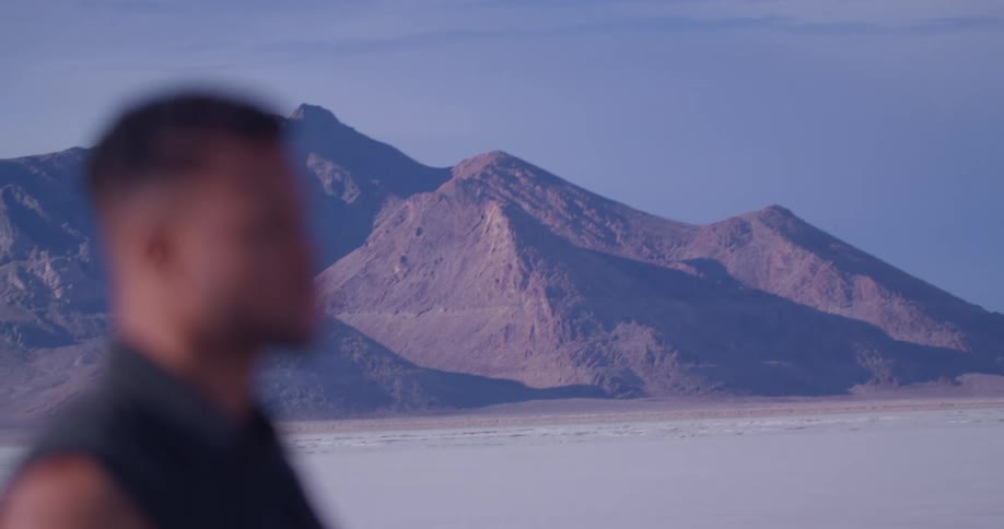 Blurry outline of a man standing in the flat plains on a desert next to the mountains