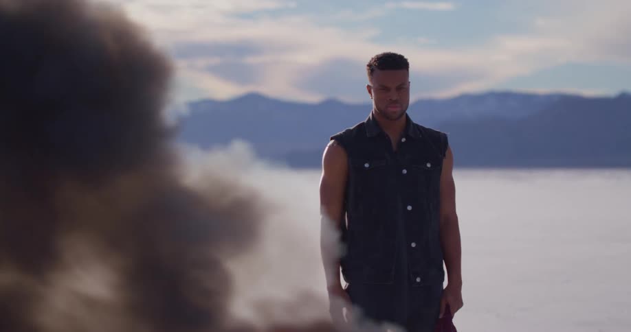 A black man is standing outside in front of a fire