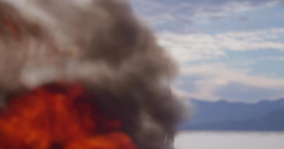 A man stands in front of a tall growing fire in the desert