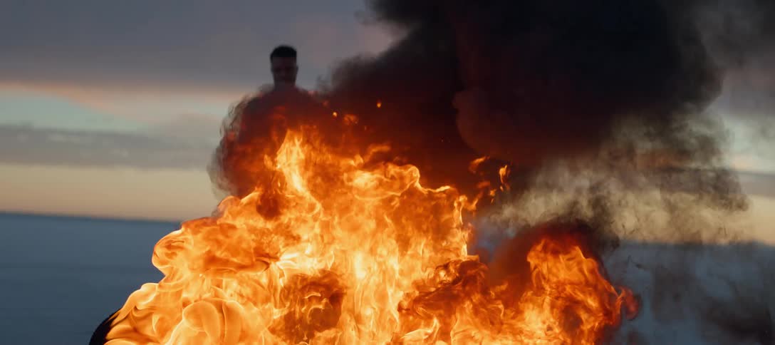 Man standing in front of a bonfire in the desert at evening