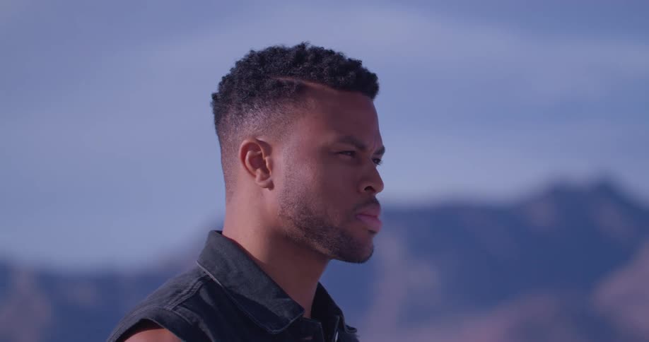 A man looks into the distance while standing outdoors in the countryside during the day
