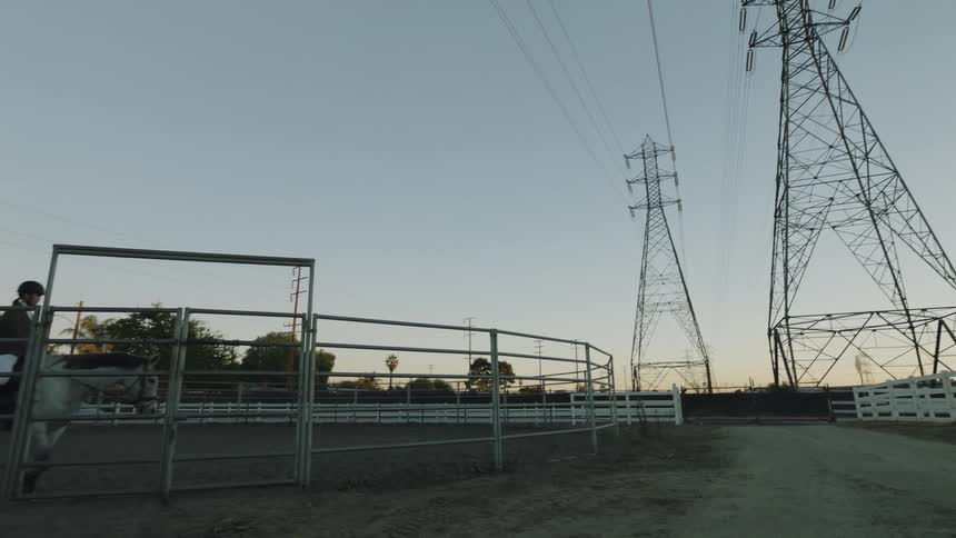 A woman rides her horse around a stable