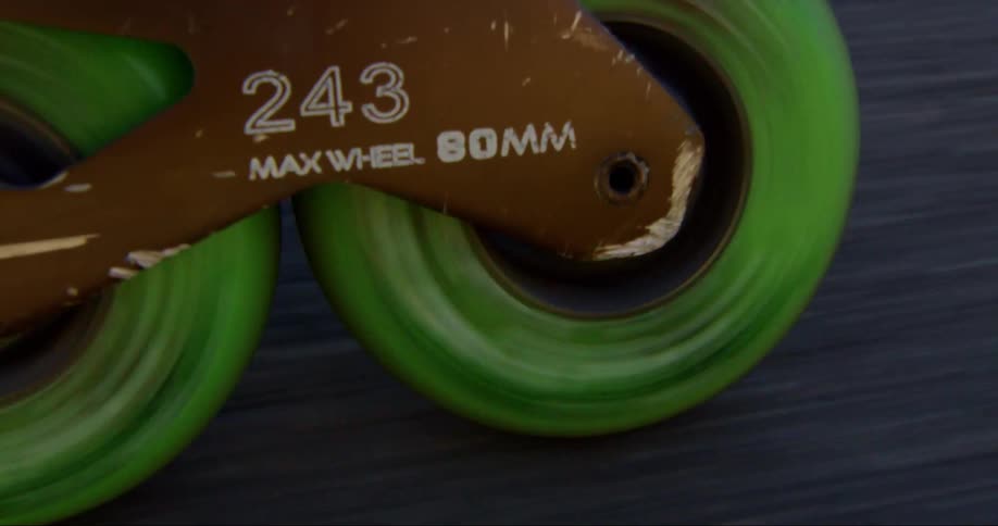 The green wheels of roller blades spin as they move across the road