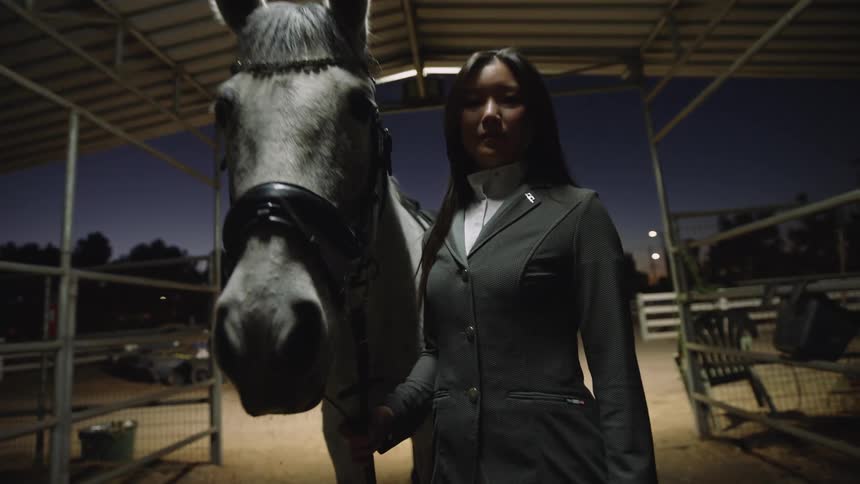 A woman poses with her horse in a stall