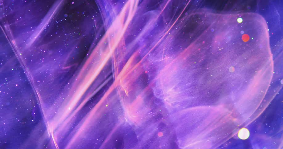 Wisps of purple and pink blending colors move across the darkness with many glowing particles