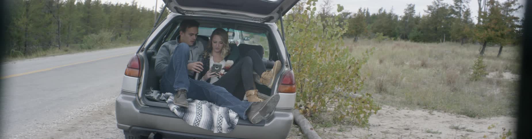 A man and woman cuddle in the back of a vehicle