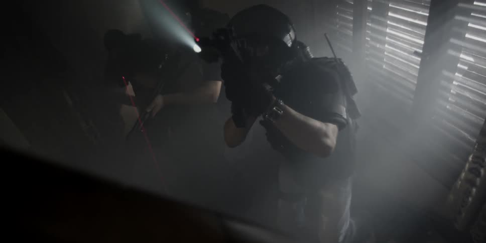 Police walk through a dark home with weapons drawn
