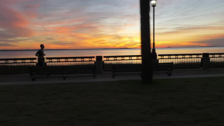 A man jogging along the shoreline during sunset