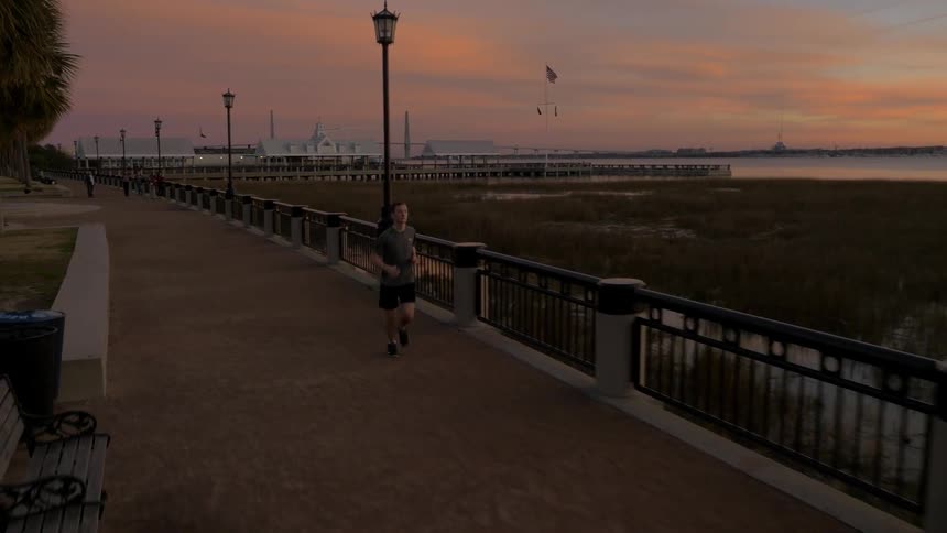 A man is jogging at sunset by the shore
