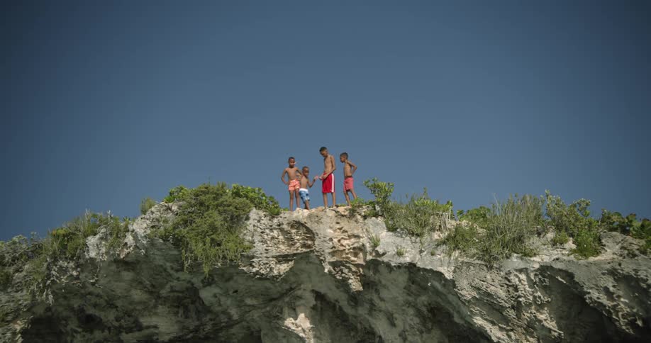 A group of boys stands on the edge of cliff