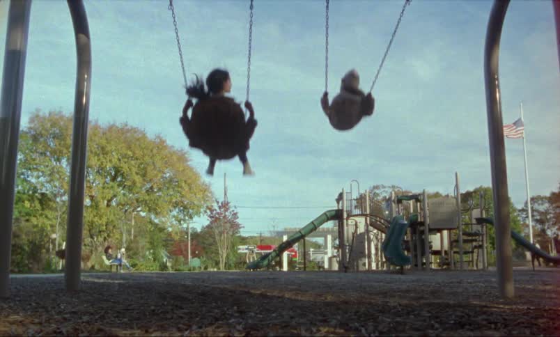 Two kids playing on swings outdoors