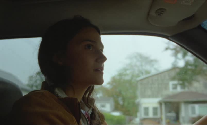 A young white woman is driving down the road in a small town