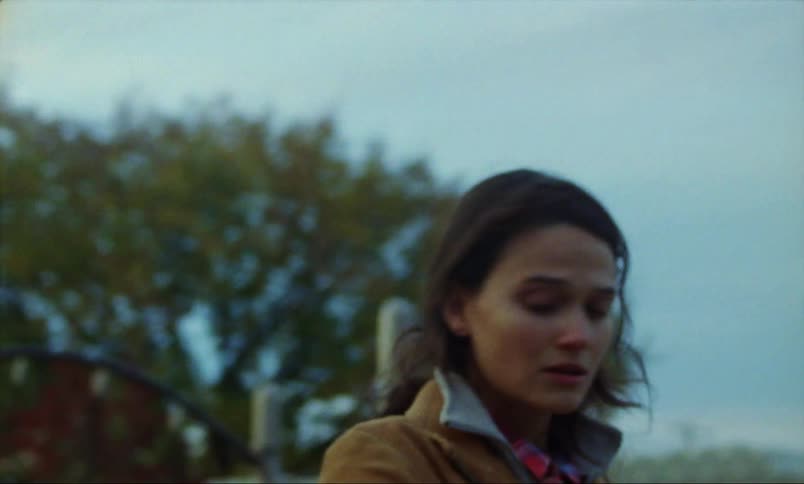 Worried woman with brown hair and jacket looks around and walks away in the playground