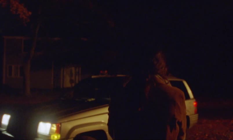 A young woman walks to a car in a neighborhood at night