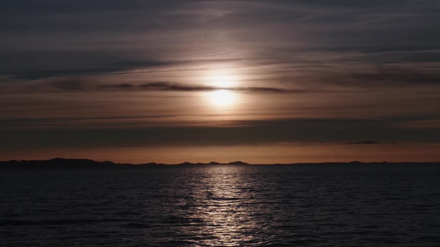 The sun sets over a calm Iceland Ocean