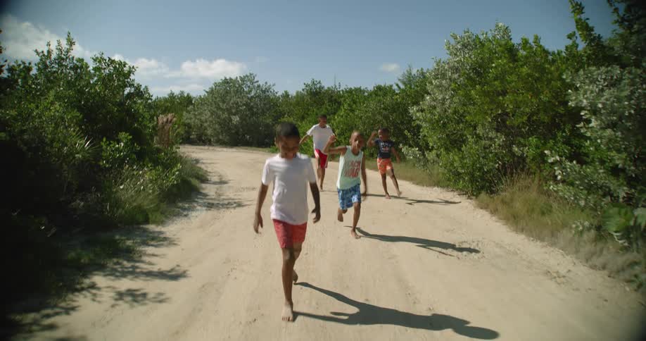 A group of young boys acting silly while walking down a dirt road
