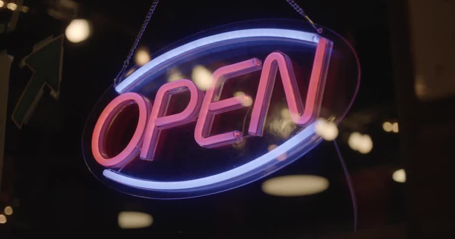 The open sign in a store window lights up