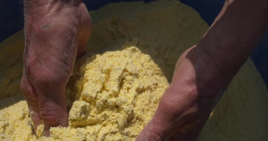 Close up of the hands of a man grabbing a handful of corn flour