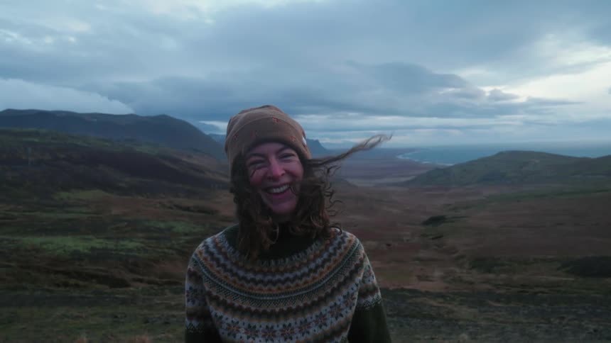A woman smiles and laughs after turning around in a canyon