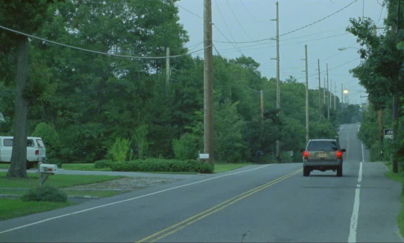 A person driving a vehicle on a paved road lined with trees and power lines
