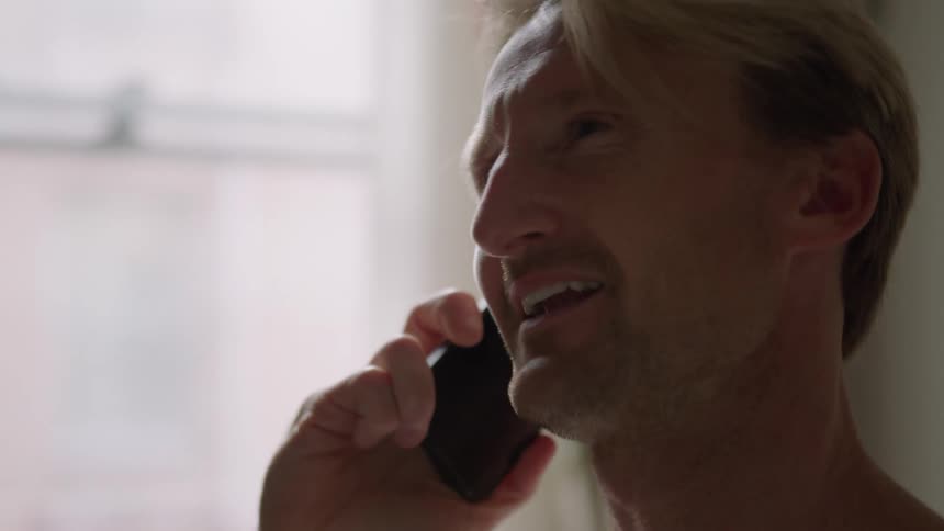 A man is talking on his cell phone in his house