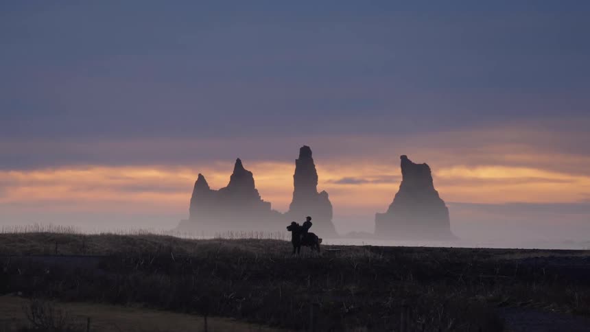 Iceland A person is riding a horse at dusk in Iceland