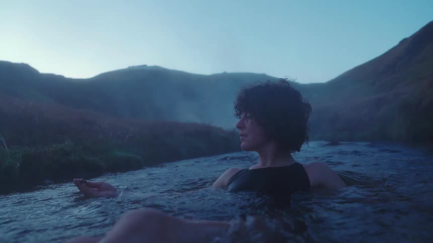 A woman floating and swimming in a stream in nature