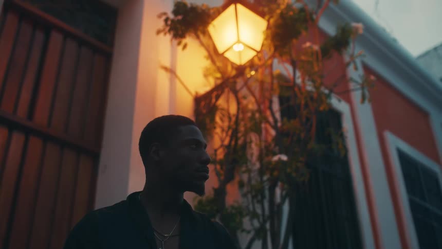 Man stands outdoors near building under outside light